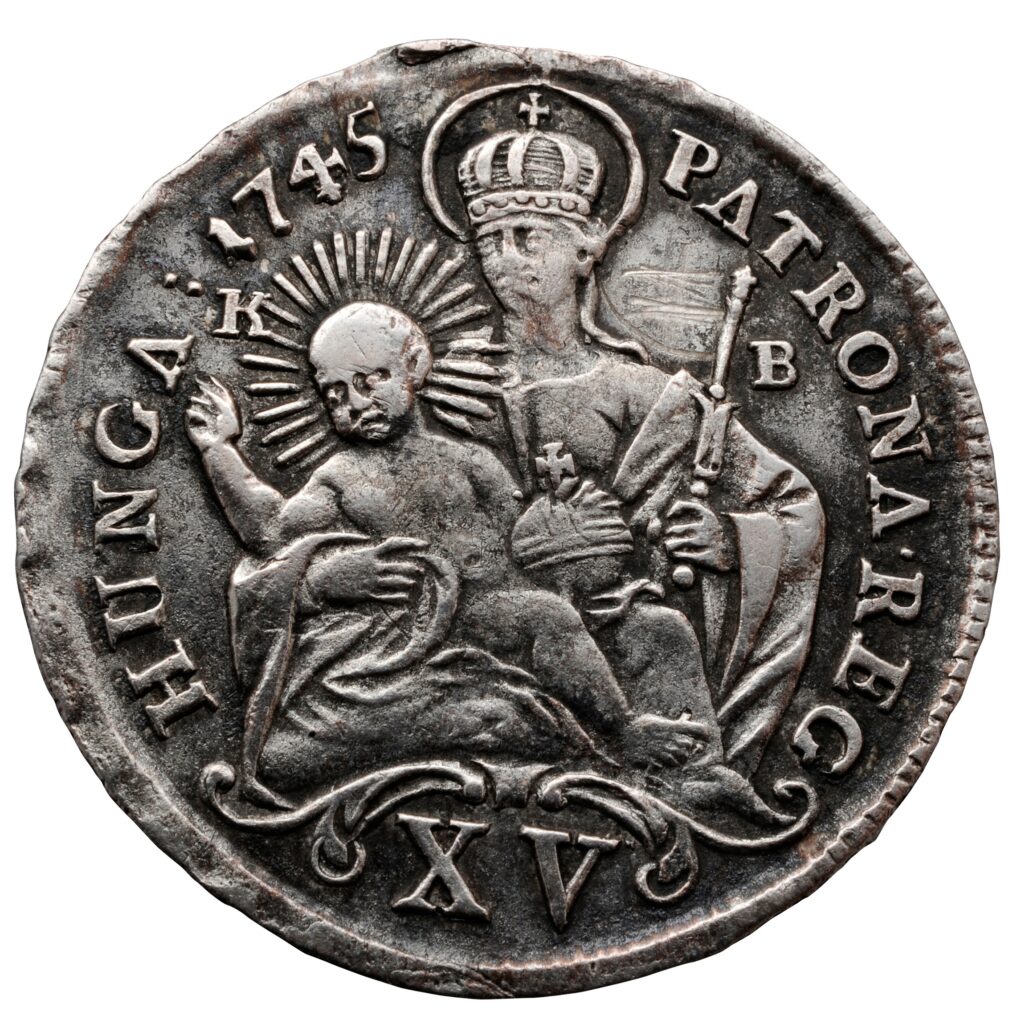 Stará strieborná minca z roku 1745 s vyobrazením korunovanej Madony s žezlom a Ježiškom, s nápisom "HUNGA. 1745 PATRONA REG." a XV v spodnej časti - artefakt spojený s história kremnickej mincovne.