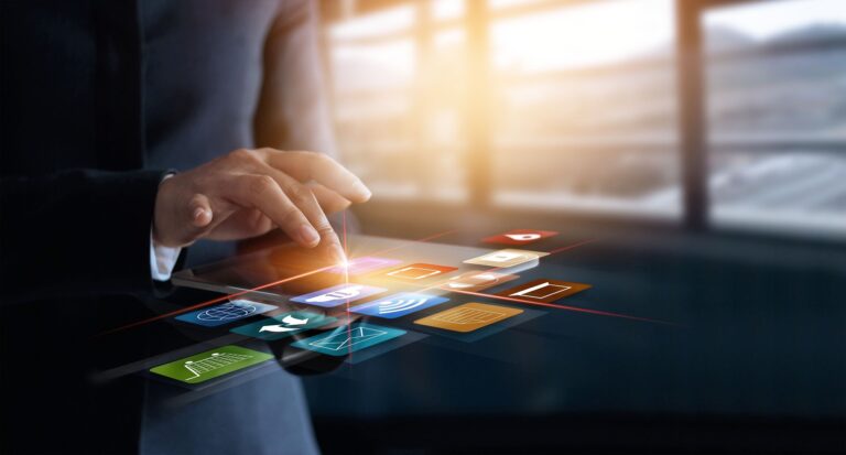 Osoba v obleku používa dotykové rozhranie s farebnými plávajúcimi digitálnymi ikonami, ktoré predstavujú rôzne aplikácie a technológie, ako napríklad bezpečné elektronické bankovníctvo, na rozmazanom pozadí kancelárie.