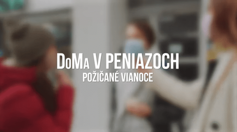 Traja ľudia, jeden v červenej čiapke, sa rozprávajú vo vnútri. Obraz je rozmazaný a prekrytý bielym textom v slovenčine: DoMa V PENIAZOCH POŽIČANÉ VIANOCE.