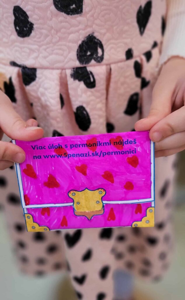 Dieťa v ružových šatách s čiernymi srdiečkovými vzormi drží farebnú, ručne kreslenú kartičku s červenými srdiečkami a textom v slovenčine o hľadaní ďalších úloh na www.5penazi.sk/permonici.