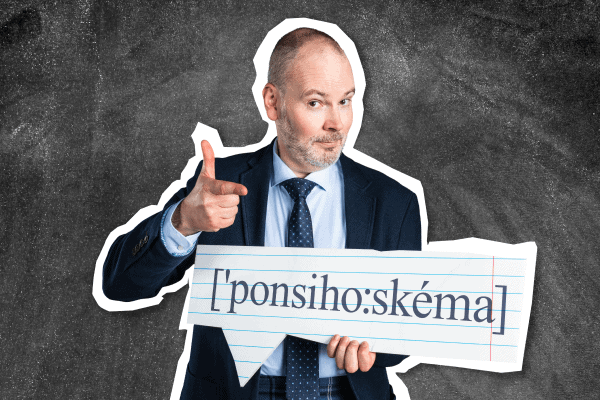 Muž v obleku ukazuje a usmieva sa, pričom drží v ruke nápis s fonetickým písmom "[ponsihoːskéma]" na pozadí tabule.