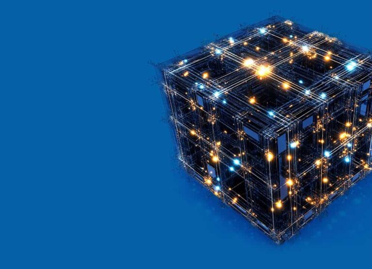 Na modrom pozadí sa nachádza svietiaca digitálna kocka zložená zo vzájomne prepojených čiar a jasných modrých a oranžových svetiel, ktorá predstavuje futuristickú technológiu alebo digitálnu sieť.