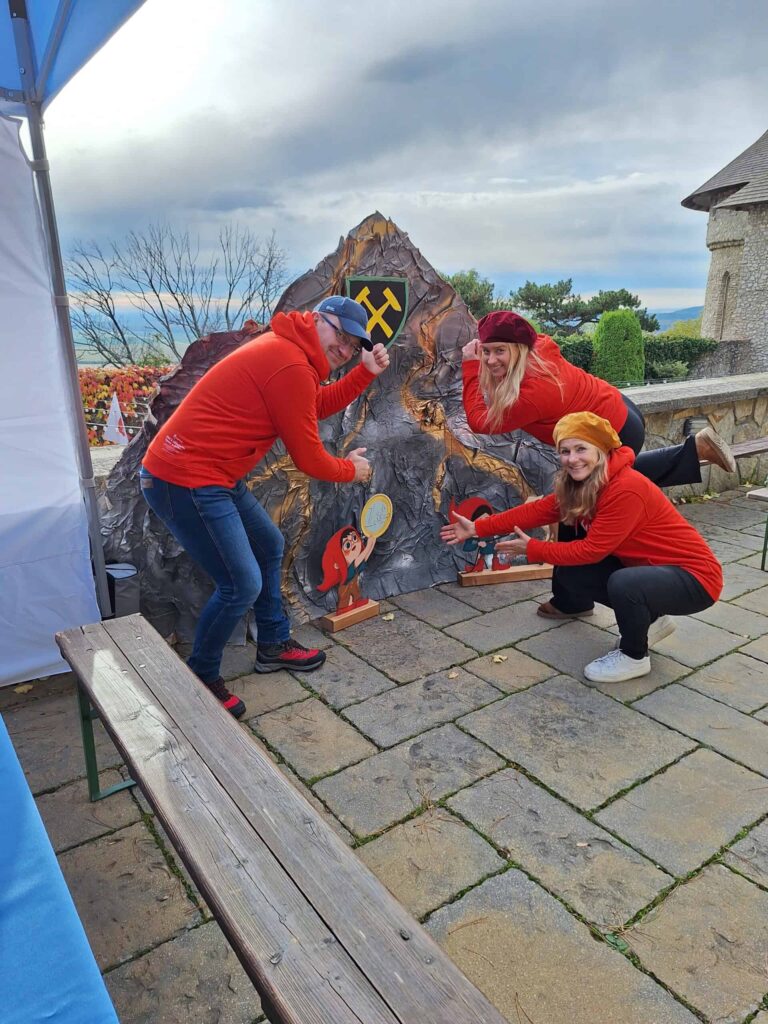 Traja ľudia pózujúci pri fotostene